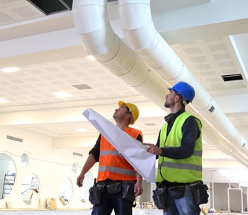 Two construction workers looking at a building