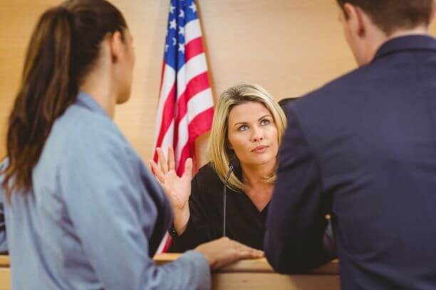 Image of attorneys speaking with judge in courtroom.