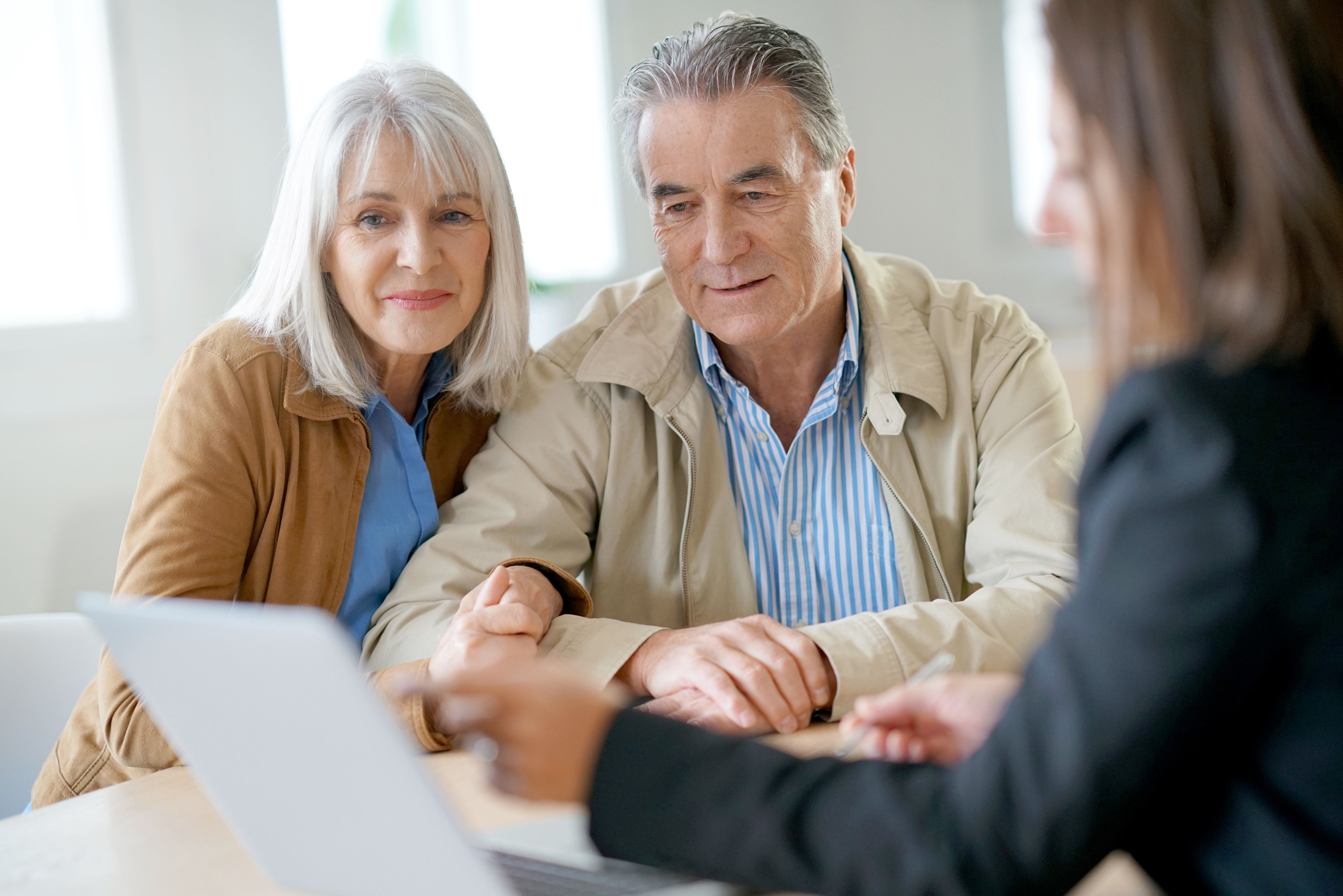 elderly couple looking at paper with professional looking woman